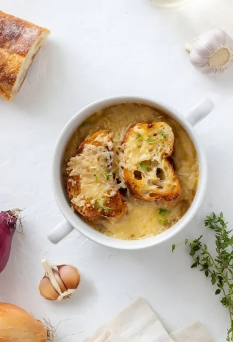 Soupe à l'oignon gratinée accompagnée de pain à l'ail, servie dans un bol en céramique