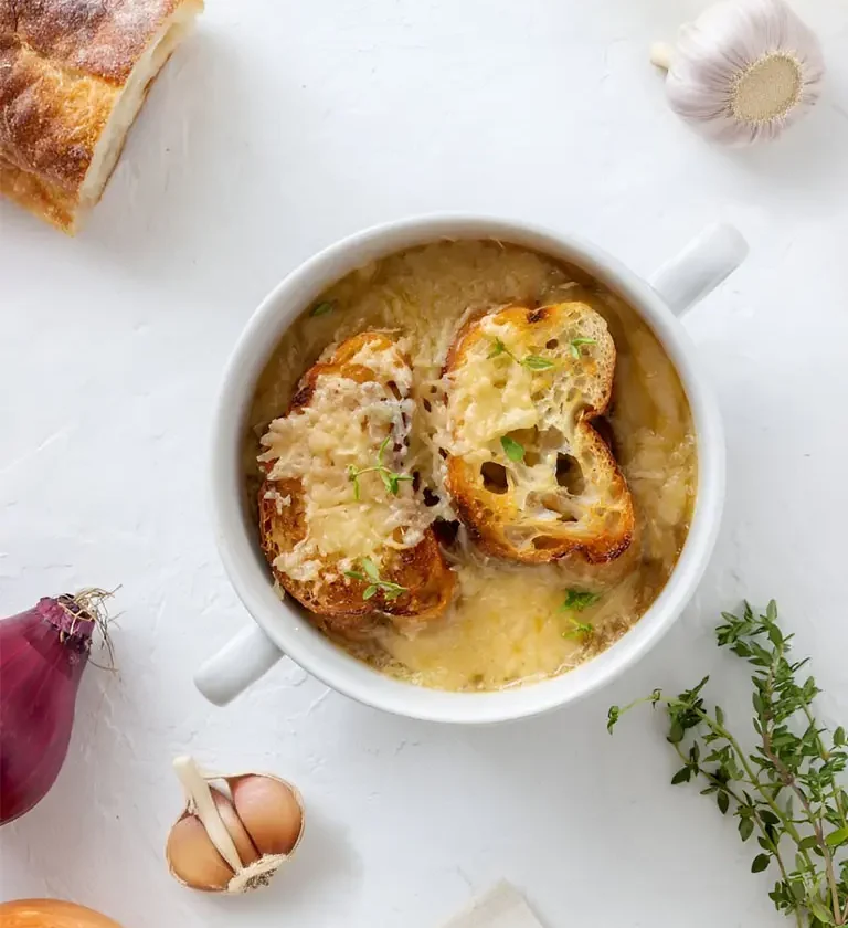 Soupe à l'oignon gratinée accompagnée de pain à l'ail, servie dans un bol en céramique