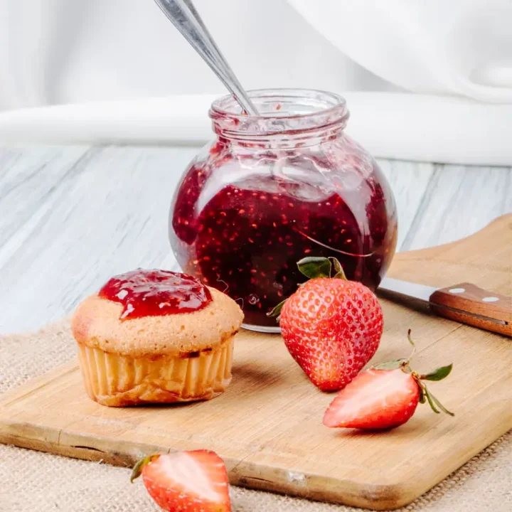 Confiture de fraises maison et un cupcake sur une table en bois, mettant en valeur une délicieuse combinaison sucrée