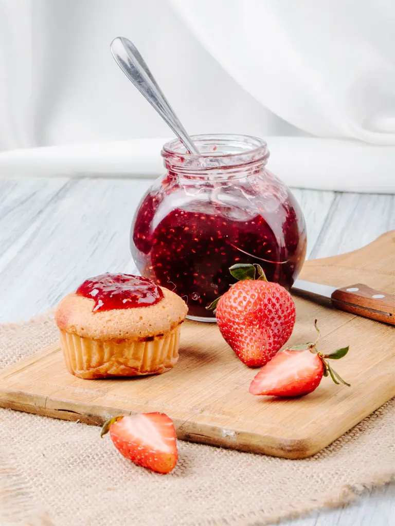 Confiture de fraises maison et un cupcake sur une table en bois, mettant en valeur une délicieuse combinaison sucrée