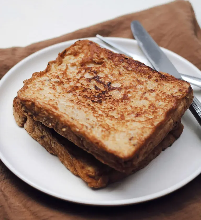 Une assiette contenant deux tranches de pain grillé, illustrant la recette du pain perdu traditionnel.