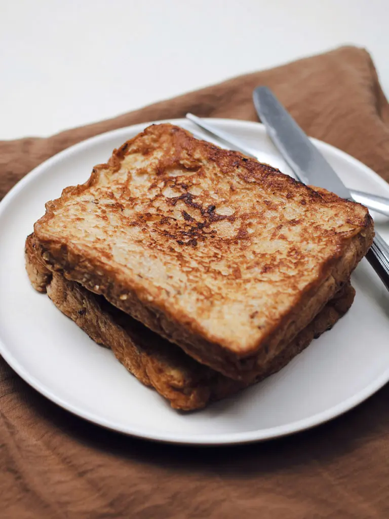 Une assiette contenant deux tranches de pain grillé, illustrant la recette du pain perdu traditionnel.