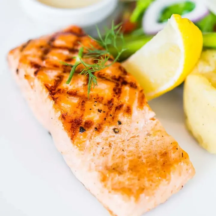 Plat de saumon grillé, pommes de terre rôties et haricots verts, illustrant une recette facile de saumon au four.
