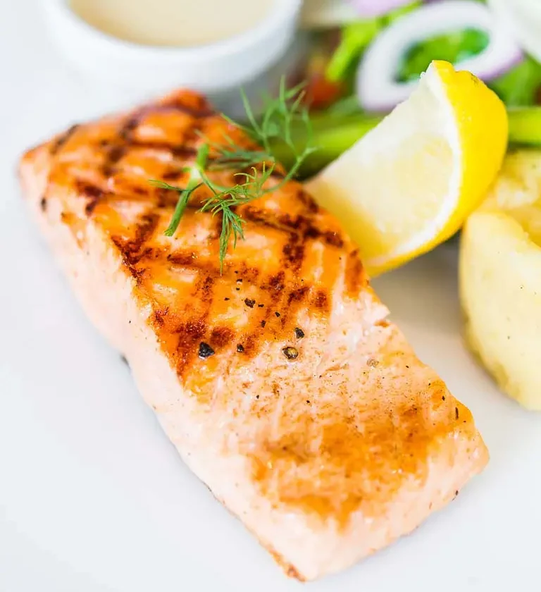Plat de saumon grillé, pommes de terre rôties et haricots verts, illustrant une recette facile de saumon au four.