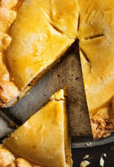 Une part de tourte à la viande sur une assiette, accompagnée d'une fourchette en métal.