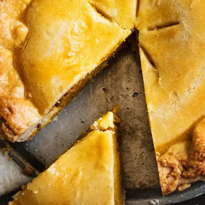 Une part de tourte à la viande sur une assiette, accompagnée d'une fourchette en métal.