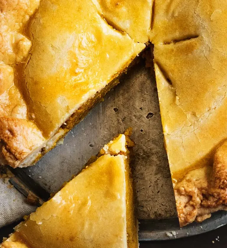 Une part de tourte à la viande sur une assiette, accompagnée d'une fourchette en métal.